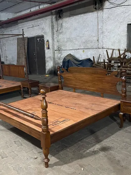 A closer look at the colonial-style bed with turned posts at the footboard and a shaped headboard, all made from rich, polished teakwood.