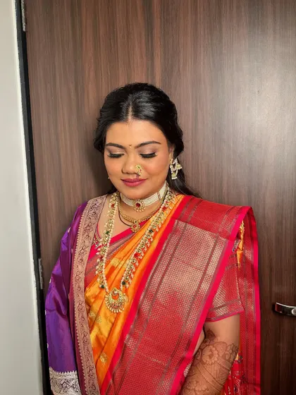 A Maharashtrian bridal look with a half-updo, adorned with fresh yellow flowers and a traditional ear chain. It's a beautiful blend of modern and traditional styles.