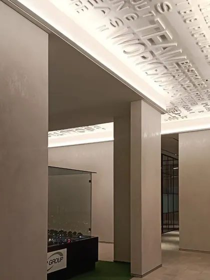 In this office space, cove lighting is used in a creative way to highlight the three-dimensional motivational text on the ceiling. This detail turns a simple transitional area into an inspiring brand statement, showcasing how light can interact with architectural features.