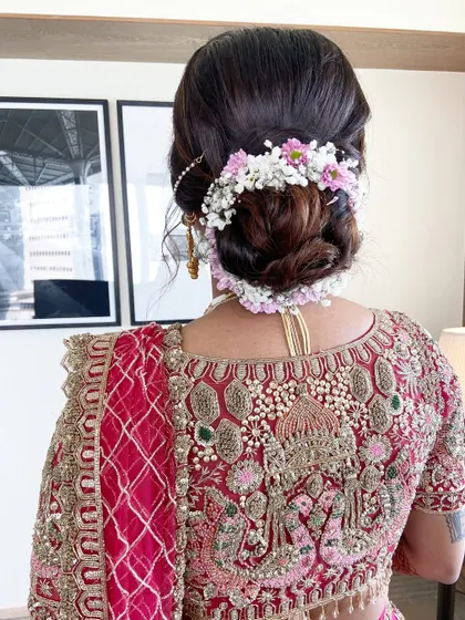 For this bridal updo, I used a mix of baby's breath and delicate pink flowers to create a soft, romantic look that complements the intricate embroidery on the bride's blouse.