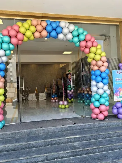 The entrance to a mermaid-themed party with a colorful balloon arch.