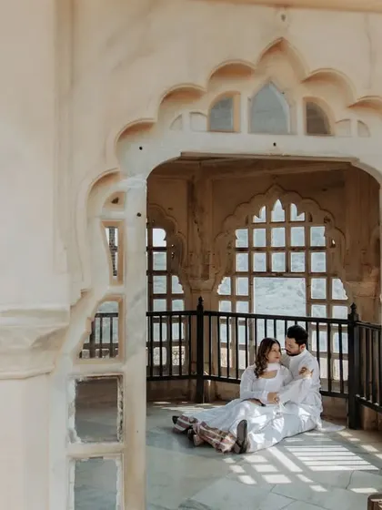 A fairytale moment captured in a sunlit palace corridor. The intricate latticework and repeating arches create a beautiful, light-filled setting for this romantic couple portrait.