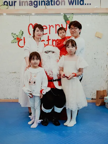 A family dressed in white poses with Santa for a festive portrait.