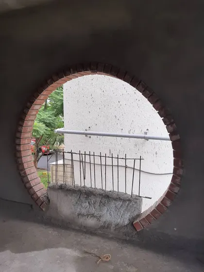 A circular window framed with traditional wire-cut bricks, seen from the interior during construction. This feature is designed to become a built-in seat, blending a classic material with a contemporary living space.