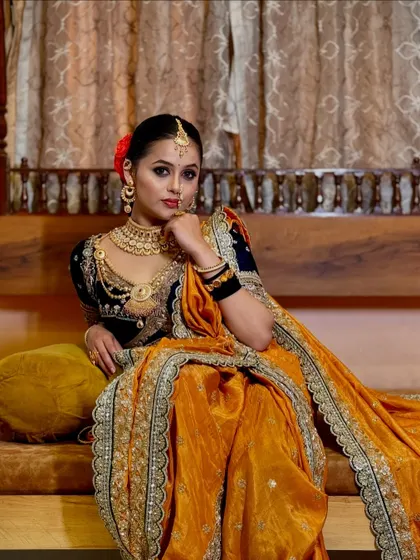 A seated pose in the Nauvari, showcasing the comfort and grace of the drape. The rich fabrics and colors create a truly royal feel.