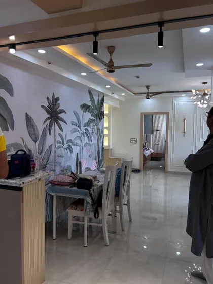 A view of an open-plan living and dining area during setup. The tropical-themed wallpaper serves as a stunning accent wall, bringing personality and color to the space.