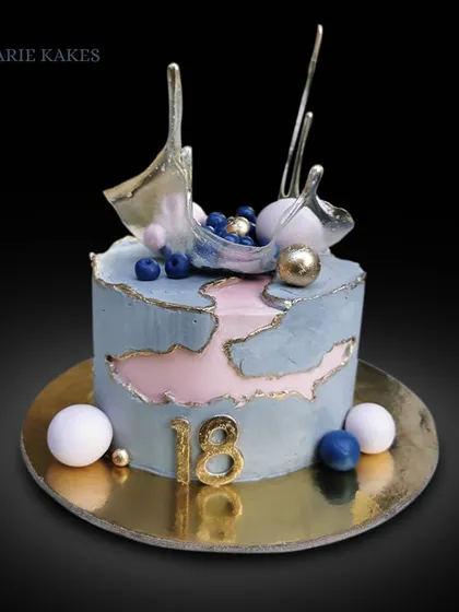 This modern fault line cake for an 18th birthday was a great opportunity to learn a new technique. It features an isomalt sail and chocolate spheres for a contemporary look.