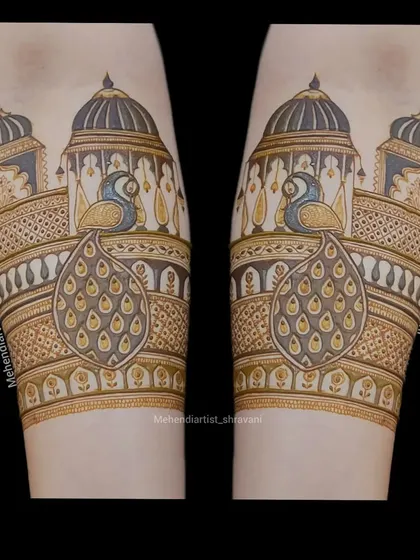 A clean and bold forearm design. This piece highlights symmetrical peacocks sitting on top of royal jharokhas, perfect for a majestic bridal look.