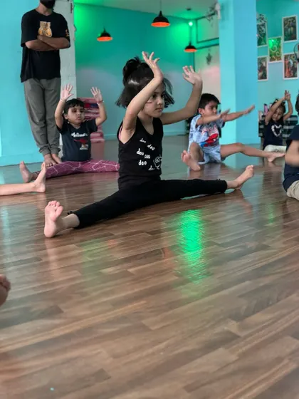 A student holding a wide-legged seated forward bend, demonstrating great flexibility and discipline.