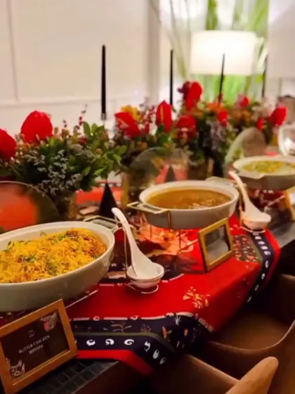 A beautifully set dinner table for a festive home party. The spread includes my Pista Badam Biryani and other main courses, presented in elegant serveware amidst a vibrant red tablescape.