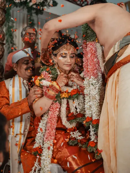 The groom ties the mangalsutra around the bride's neck, a defining moment of their union, captured amidst a shower of petals.
