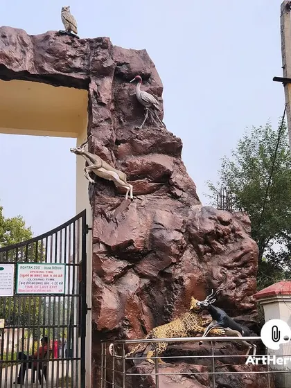 A close-up of the right pillar of the Rohtak Zoo gate, showing a dynamic scene with a leopard chasing antelope, all sculpted with realistic detail.