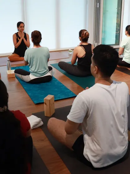A class in session, with students seated in meditation. This view highlights the depth of the studio and the sense of community as everyone practices together.