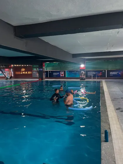 Guiding a small group through various movements in the pool. The use of props like pool noodles makes the practice accessible and fun for everyone.