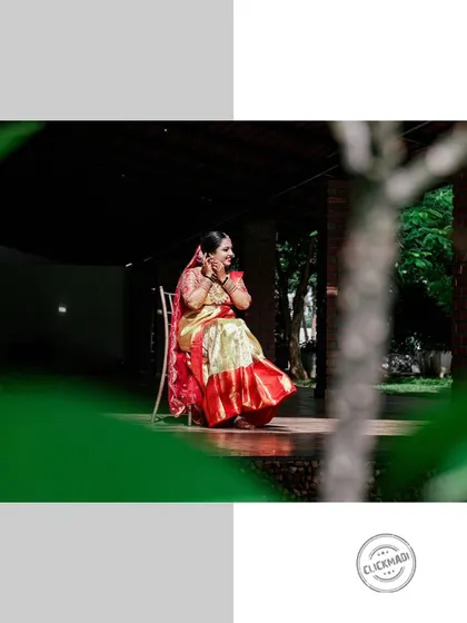 An artistic shot of the bride sitting alone, framed by lush greenery, capturing a quiet moment of contemplation on her wedding day.