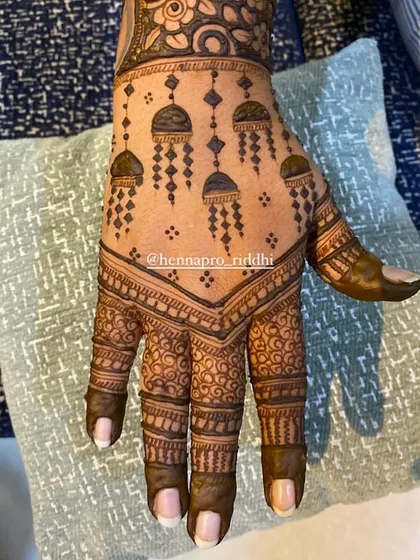 Kaliras in the house! This minimalist back-hand design features delicate hanging kalira motifs, a chic and modern way to incorporate a classic bridal accessory into your henna.