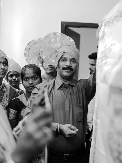 A candid black and white moment from a Maharashtrian wedding ceremony, capturing the expressions of the family members involved in the rituals.