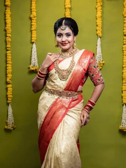 A full view of this stunning bridal look. The jewellery is layered perfectly to match the grandeur of her off-white and red silk saree.
