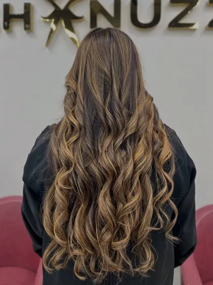 The full length of this light brown and blonde blend, styled in glamorous curls.
