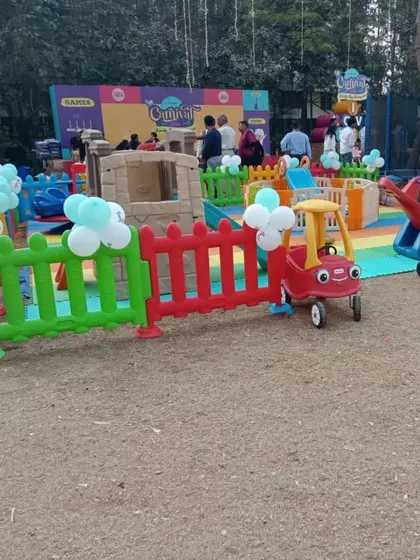 This playzone was set up on a rustic ground for a community event. It includes a playhouse, ride-on cars, and other equipment, all safely arranged on colorful foam mats to ensure a clean and secure play surface.