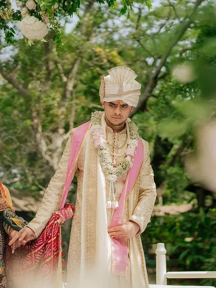 A couple stands together during their ceremony, framed by lush greenery and floral decor.