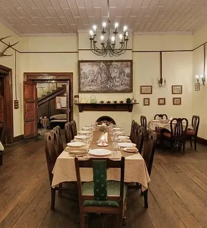 Another view of the dining room, featuring a large fireplace and traditional artwork, creating a cozy and elegant atmosphere for guests.