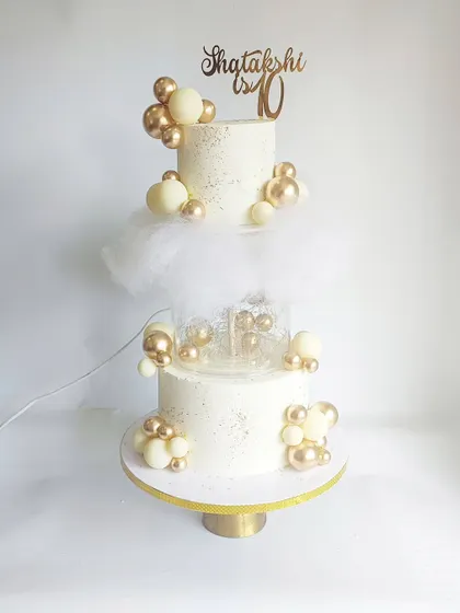 A dreamy white and gold tiered cake with a 'floating' cloud effect. This magical design is perfect for a fairytale wedding or a heavenly 10th-anniversary celebration.
