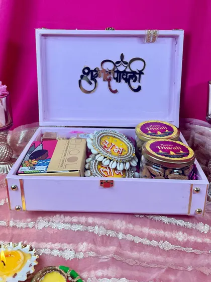 The inside of our pink Diwali trunk box. It's filled with jars of delicious dry fruits, traditional 'shubh laabh' hangings for the home, and other festive goodies, making it a complete gift.