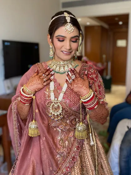 Simran admiring her stunning jewelry. Her makeup is perfectly balanced to complement the intricate details of her necklace and earrings.