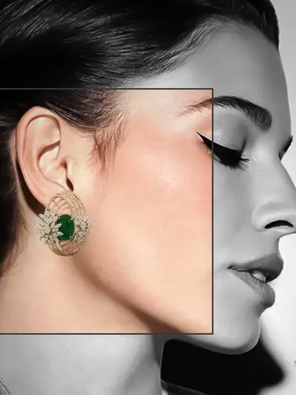 A creative shot highlighting the emerald and diamond stud earring, with a black and white filter on the model to draw all attention to the jewel's color and brilliance.