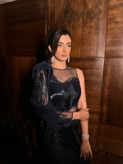 This shot captures the moodiness and glamour of the look. The dark, dramatic outfit is complemented by a makeup look that is equally powerful.