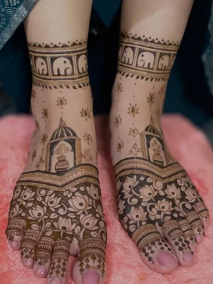 This foot mehendi is filled with traditional elements. It features a kalash, lotus flowers, and a band of elephants, creating a beautiful and auspicious design.