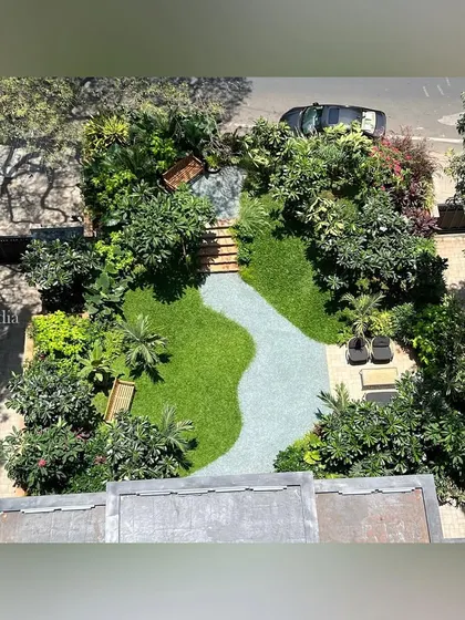 This top-down aerial shot provides a complete overview of the entrance garden's layout. It clearly shows the flowing shape of the gravel path, the placement of seating areas, and the rich variety of trees and shrubs.