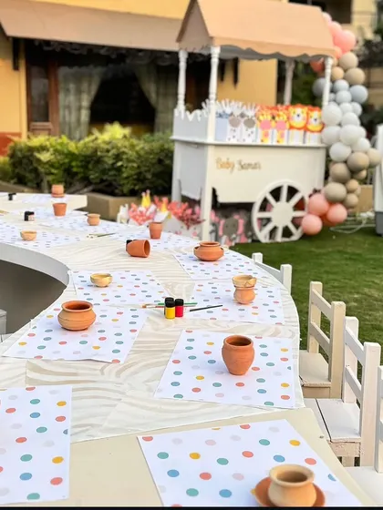 A pottery painting station set up for the little guests. The curved table and colorful placemats create an inviting and creative corner for kids' activities.