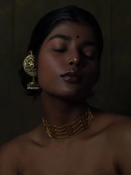This serene portrait is all about the interplay of light and shadow. The golden tones of the jewellery and the glossy lips create a rich, luxurious feel.