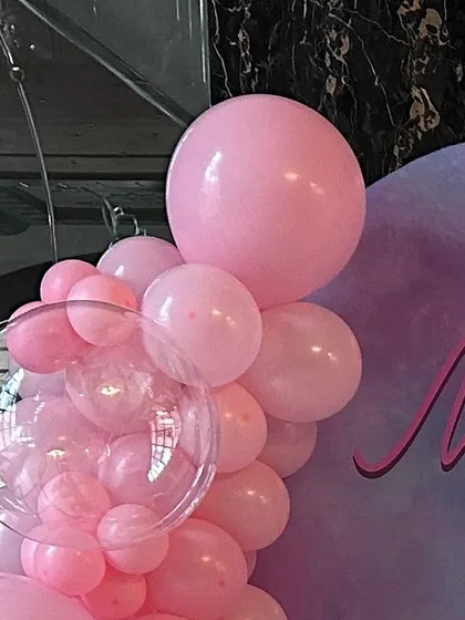 A detail shot of a pink balloon garland for a unicorn-themed party. The arrangement includes a clear bubble balloon filled with smaller pink balloons for a unique touch.