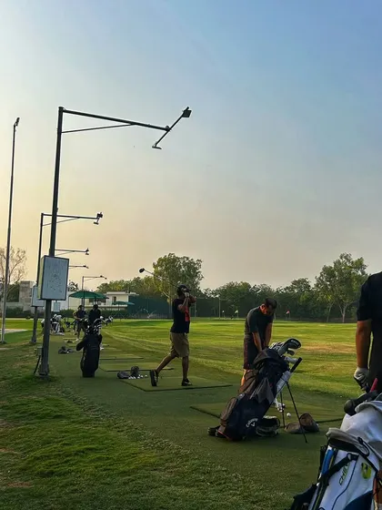 The driving range during the golden hour, with long shadows and warm light creating a beautiful scene.