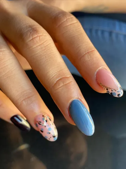 A cool, mismatched set featuring a mix of solid colors, dalmatian spots, and a glittery French tip.