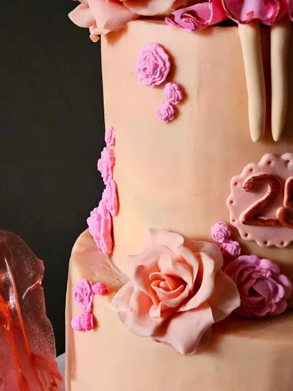 This close-up highlights the handcrafted sugar rose and the "25" marker for the daughter's birthday, showing how the cake celebrates both individuals.