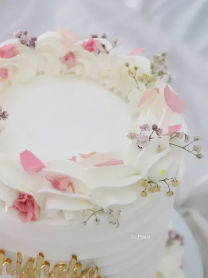 A top-down view showing the delicate arrangement of flowers and petals on this custom engagement cake.