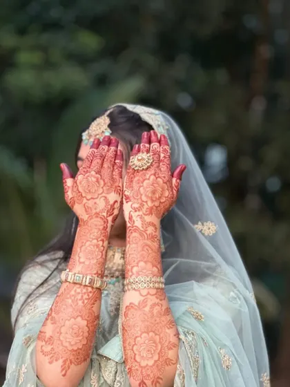 A beautiful shot of a bride showing off her mature henna stain. The floral design has developed into a rich reddish-brown color, a testament to the quality of natural henna.