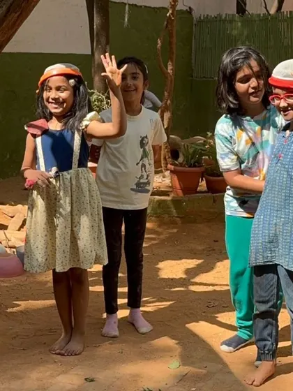 The "bride" and "groom" wave to their friends, their headdresses fashioned from sand sieves. The resourcefulness and creativity in their pretend play is always a joy to witness.