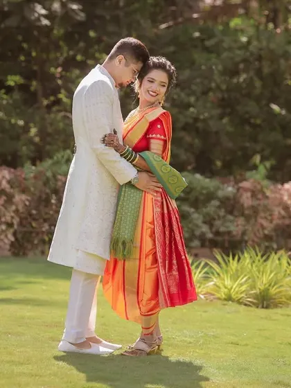 A beautiful full-length portrait of the couple in a garden setting, showcasing their elegant traditional outfits and their comfortable connection.