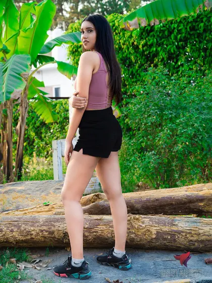A full-length outdoor shot of a model in athletic wear. The natural environment with logs and greenery provides a great context for fitness or lifestyle-oriented fashion photography.