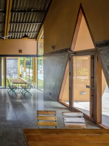 The interior features unique triangular doorways and an open floor plan that responds to the context of a highway restaurant. The design incorporates features from local architecture, like sloped roofs and fenestrations.