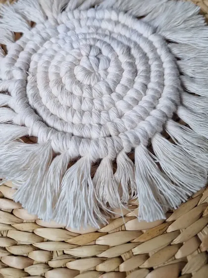 A close-up of my spiraled macrame coaster, showing the texture of the natural cotton cord and the soft fringe. It's all in the details.