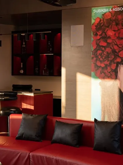 This entertainment lounge features a home theatre, a chic bar, and a bold black-and-red color scheme that exudes energy and sophistication.