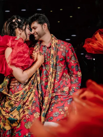 A quiet moment between the couple amidst the celebration. The rich textures and colours of the Mehendi decor, from the floral arrangements to the patterned textiles, create a warm and intimate setting.