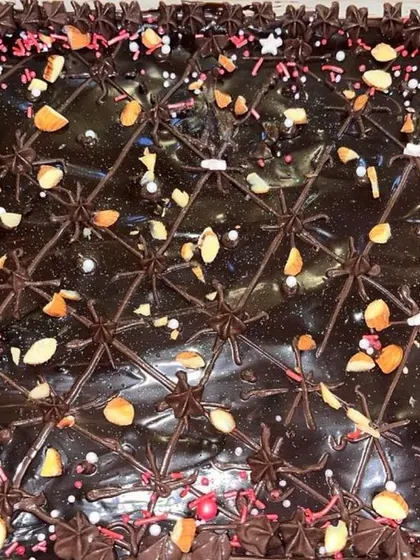 This Brownie Delight tray is decorated with piped chocolate and chopped nuts, making it a beautiful and delicious centerpiece for your dessert table.