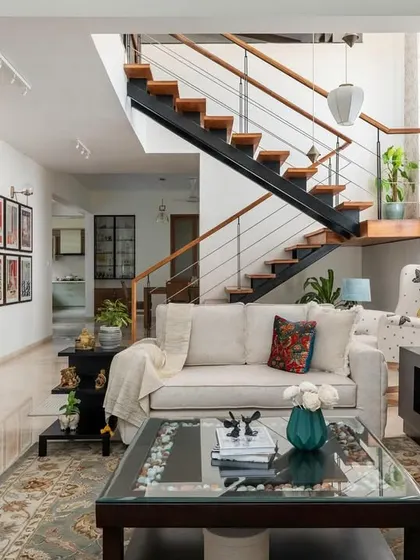 The interconnected living, dining, and stairway area in the 'House of Kismish' creates a grand, open feel. We designed this formal living space for conversation, which transitions into a cozy reading nook under the high ceiling, perfect for moments of solitude.